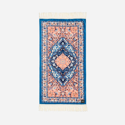 A beach towel with a printed velour front featuring a geometric pattern in a mix of blue and orange hues, with a terry looped back, displayed against a white background.