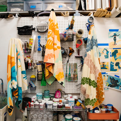 Sustainable cotton towels displayed on art studio pegboard with paint supplies.