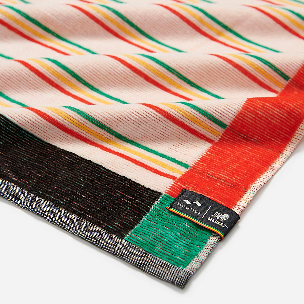 Cotton towel with colorful diagonal stripes and corner label on white background.