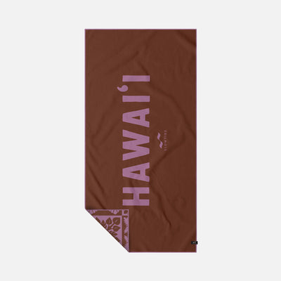 Beach towel, brown, sand-free, pink HAWAIʻI letters, floral pattern on folded corner.