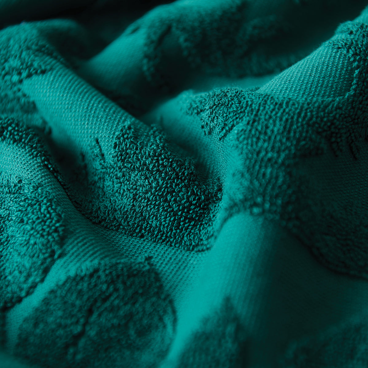 Teal velour towel with raised textured pattern and soft wavy folds.