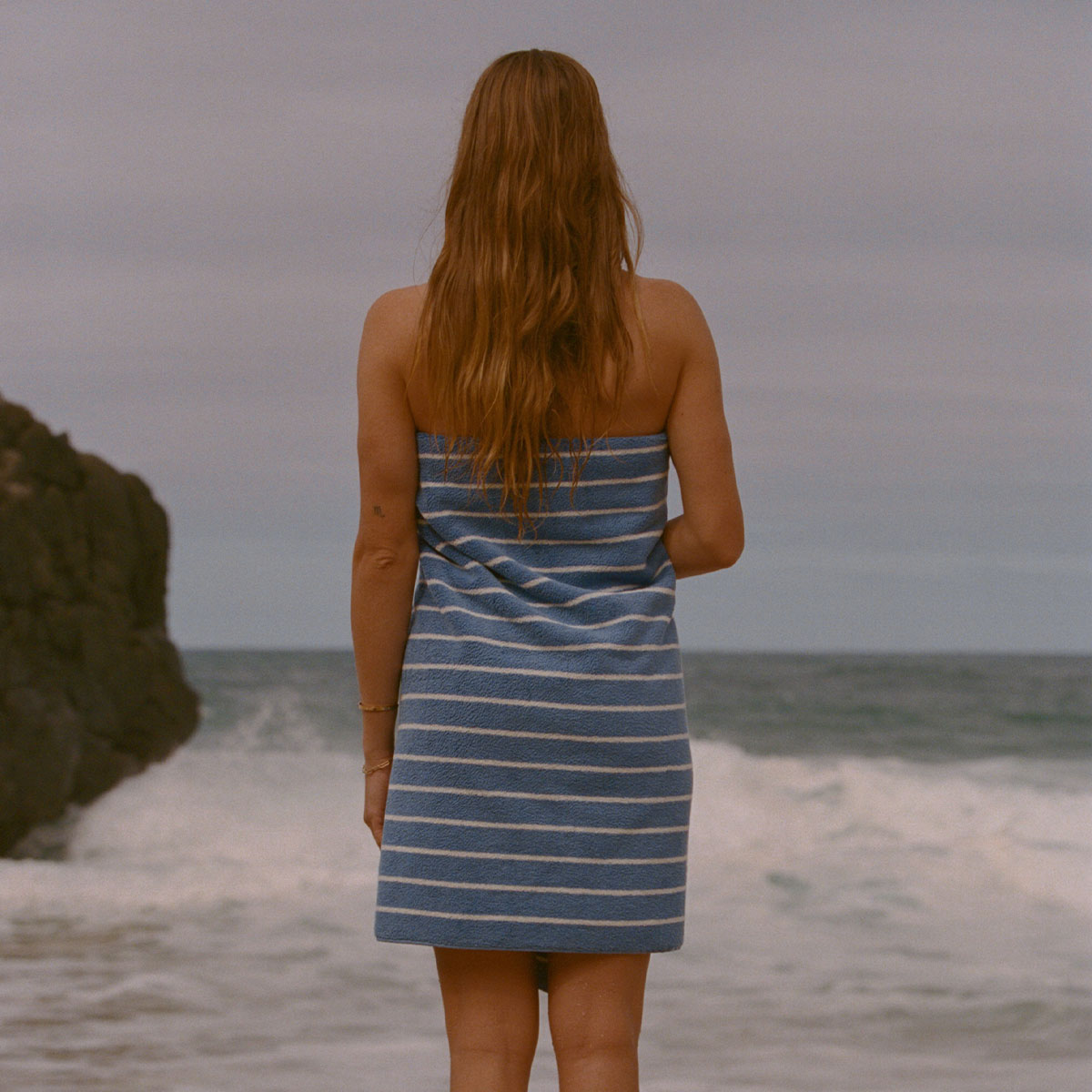 Striped changing poncho with hood, terry fabric, beach setting.