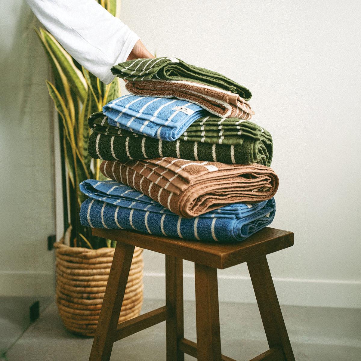 Folded ultra-plush cotton striped towels on a wooden stool.