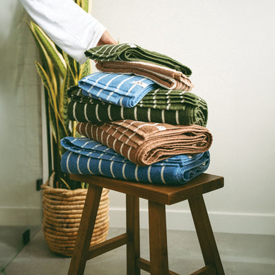 Folded ultra-plush cotton striped towels on a wooden stool.