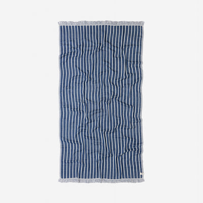 Towel with navy and white pinstripes, fringe edges, laid flat.