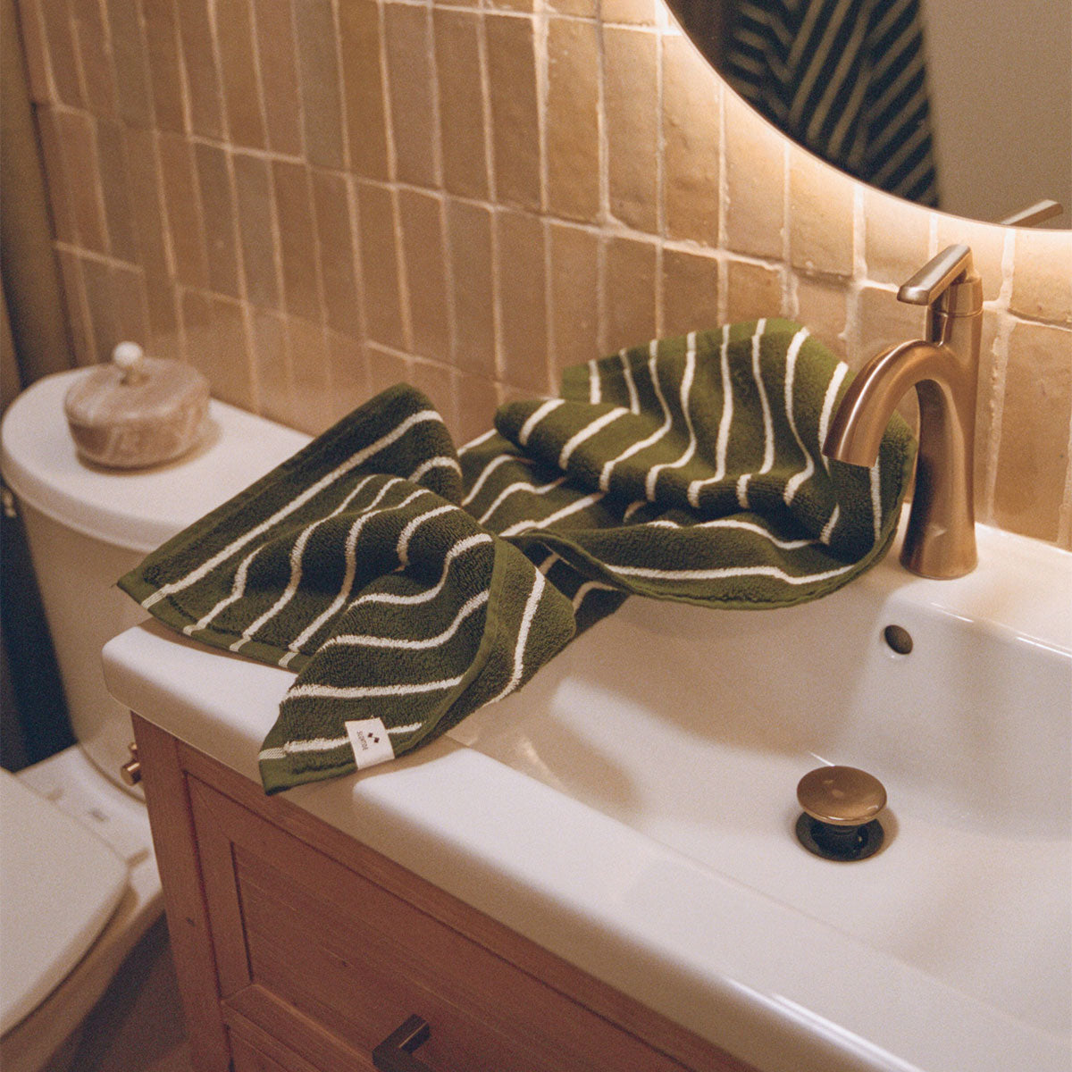 Plush hand towel with green stripes on sink.