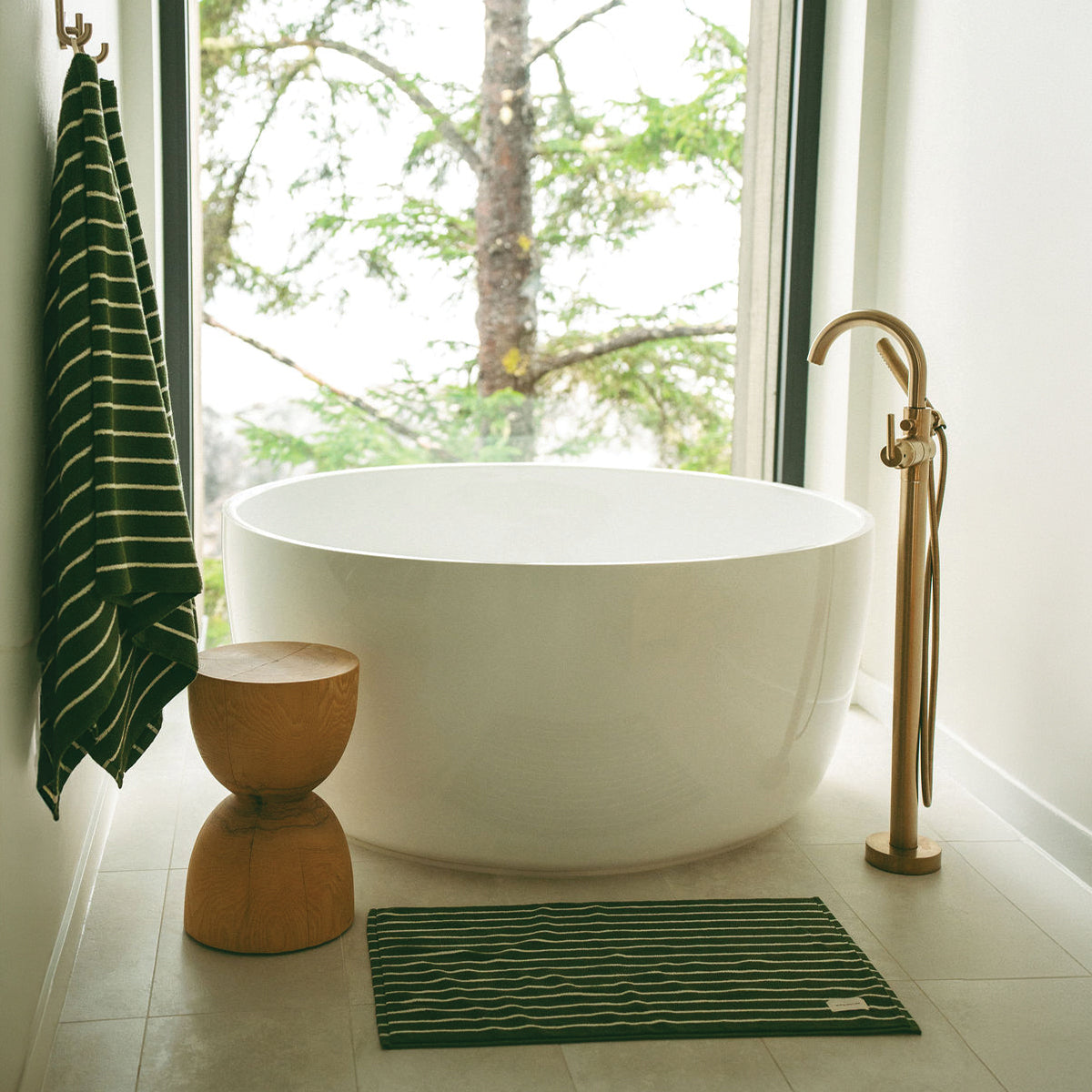White freestanding bathtub with brass faucet and plush absorbent towels.