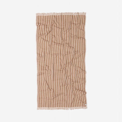 Oversized terracotta towel with white stripes and fringed edges on a plain background.