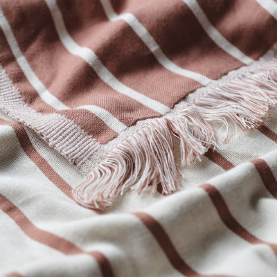 Beach blanket, woven fabric with brown and white stripes and fringe edging.