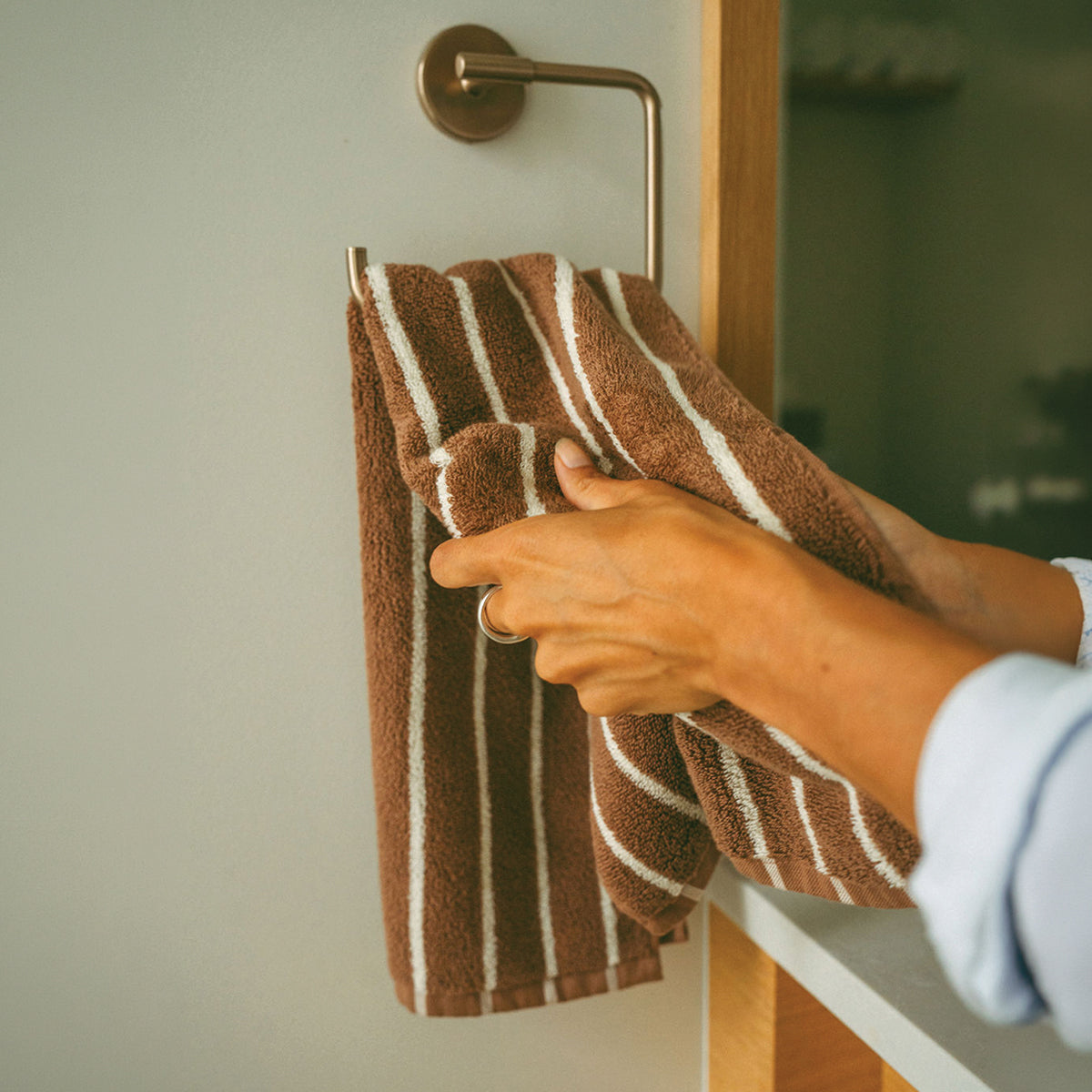 Hand towel in brown and white stripes on a wall rack.
