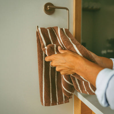 Hand towel in brown and white stripes on a wall rack.