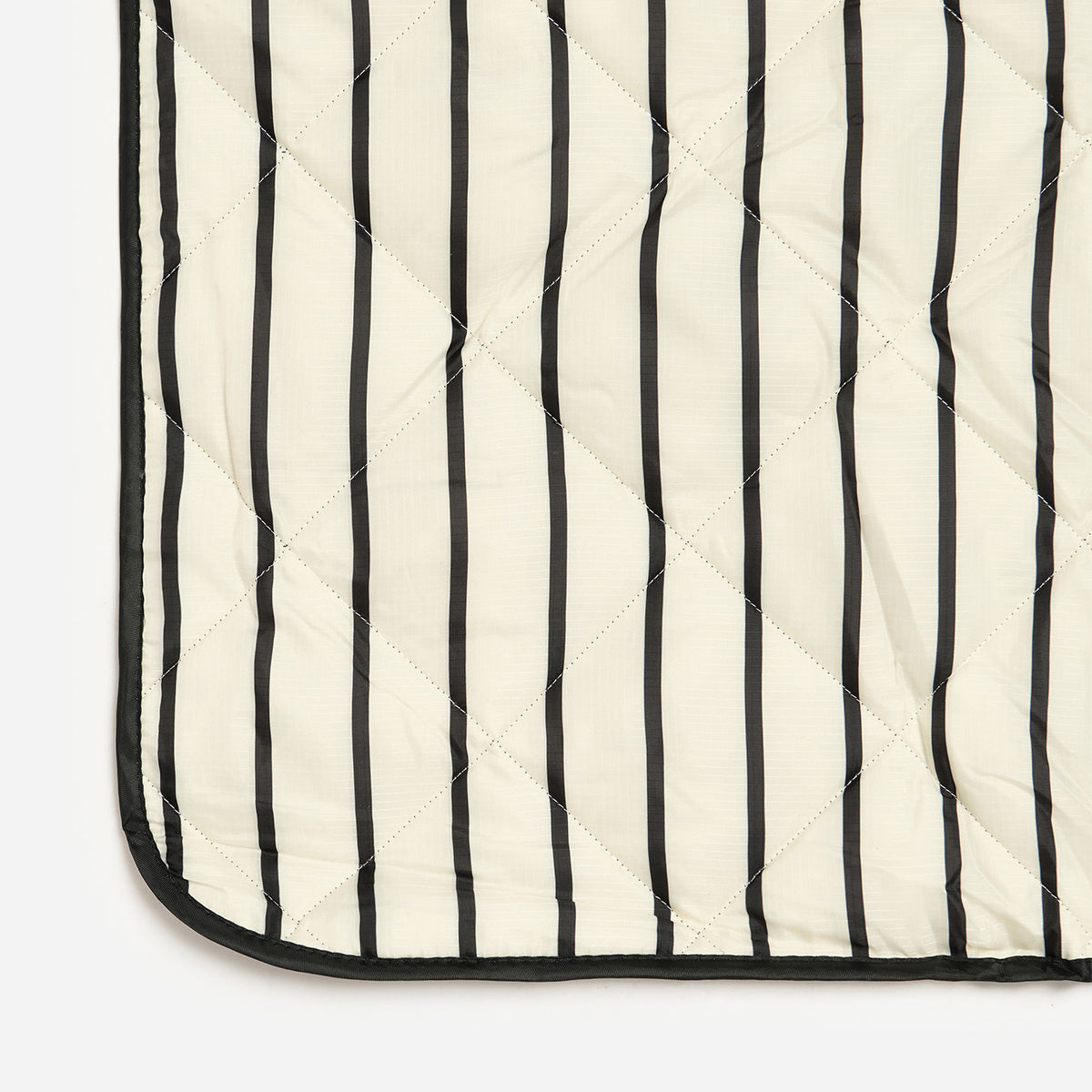 Quilted picnic blanket with water-resistant black and white vertical stripes.