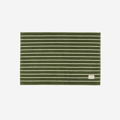 Cotton bath mat with white stripes and small label, absorbent for bathroom use.