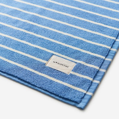 Cotton towel with white stripes, absorbent and soft, suitable for use as a bath mat.