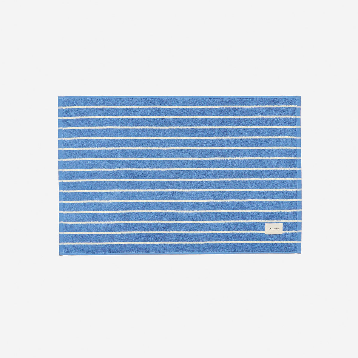 Blue cotton bath mat with thin white stripes and small label.