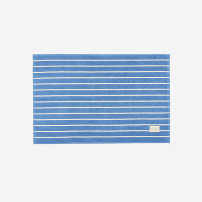 Blue cotton bath mat with thin white stripes and small label.