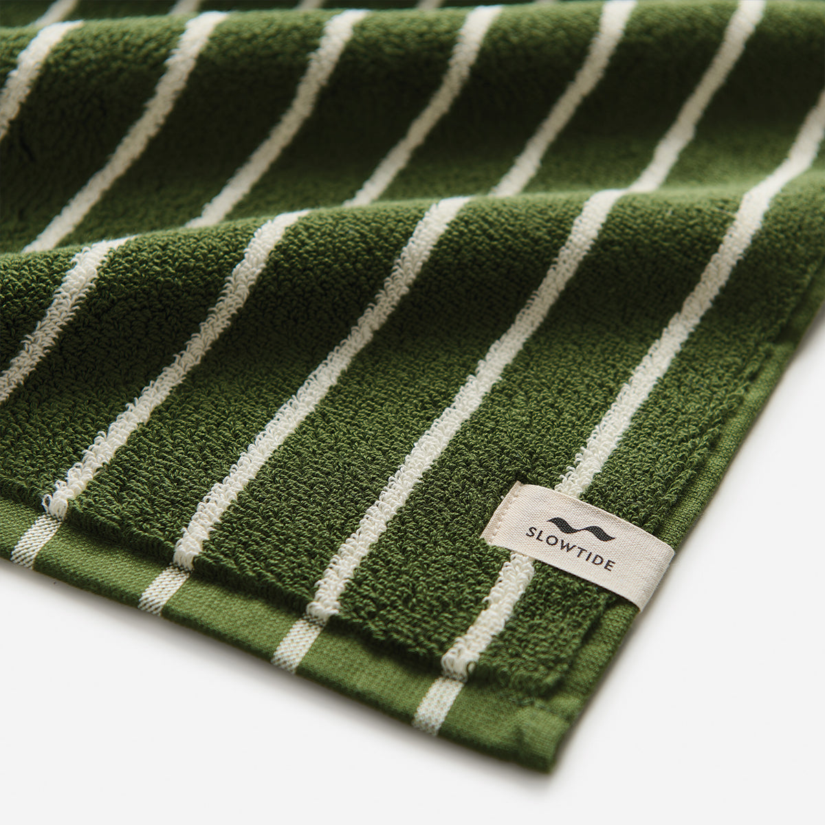 Oversized green towel with white stripes and visible corner tag.