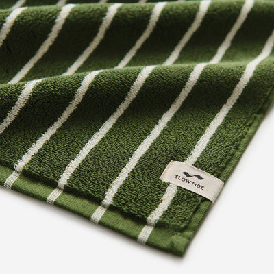 Oversized green towel with white stripes and visible corner tag.