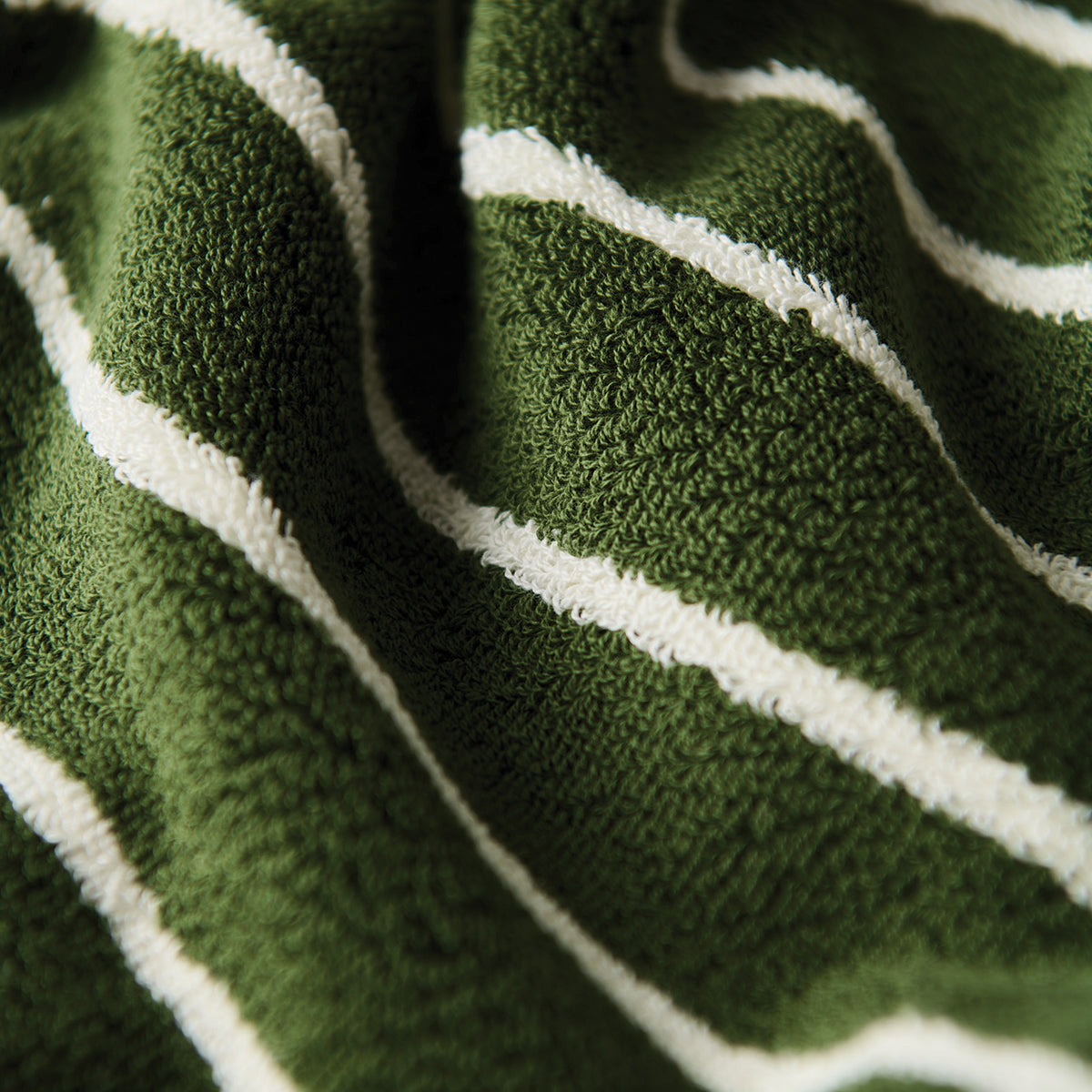 Towel poncho, green with textured fabric and white diagonal stripes, close-up view.