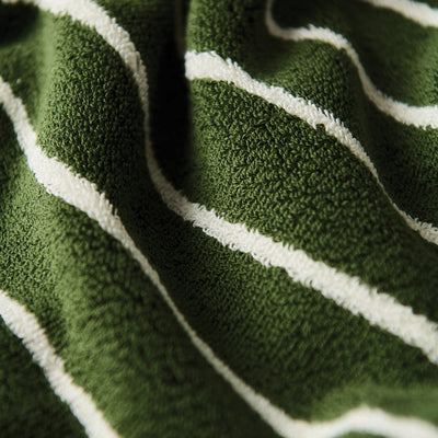 Towel poncho, green with textured fabric and white diagonal stripes, close-up view.