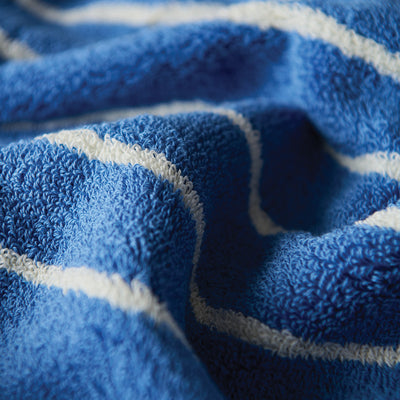 Blue quick dry towel with white stripes, textured fabric shown in close-up.