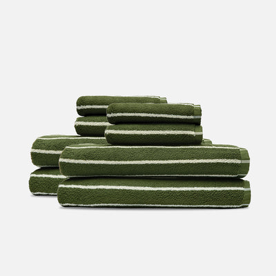 Plush green and white bath towels stacked in three rows.