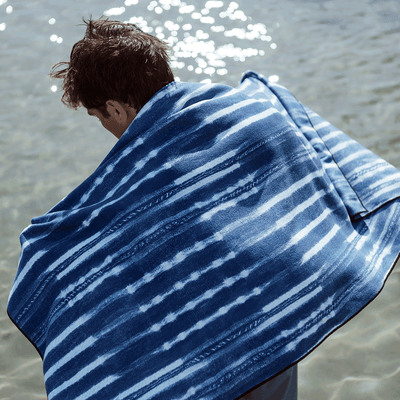 Beach towel, quick-dry fabric, blue and white stripes by the water.