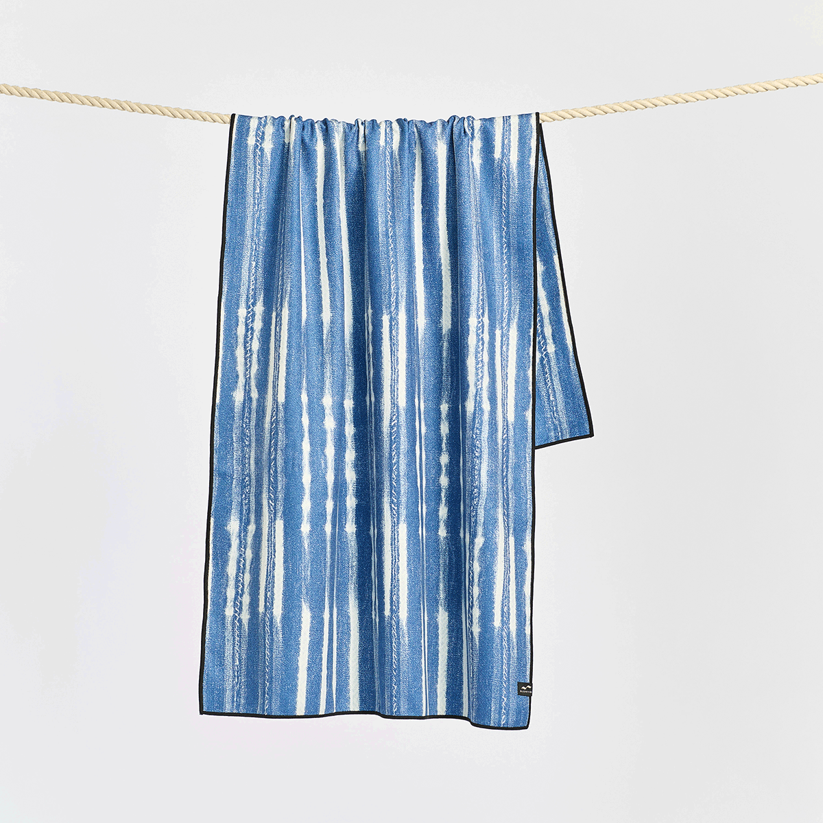 Beach towel, quick-drying fabric, blue and white stripes, hanging on rope.