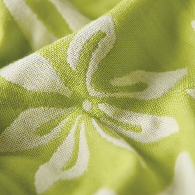 Green cotton towel with white floral pattern, close-up of soft gauzy fabric folds.