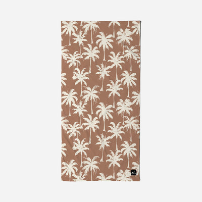 Velour towel with white palm tree pattern and small black tag in the corner.