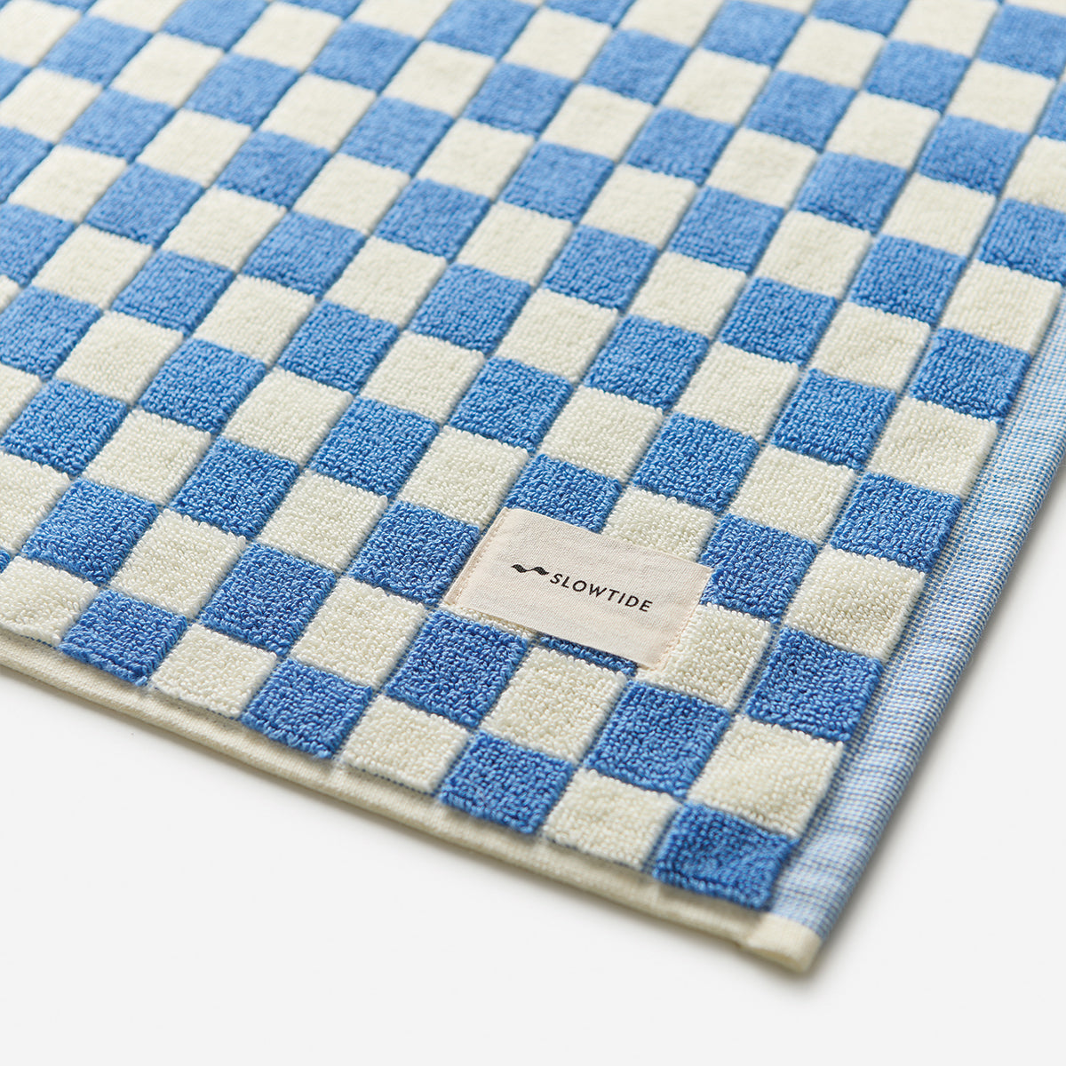 Cotton bath mat with blue and white checkered pattern, absorbent design.