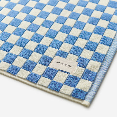 Cotton bath mat with blue and white checkered pattern, absorbent design.