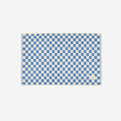 Cotton bath mat with blue and white checkerboard pattern, small label at bottom right.