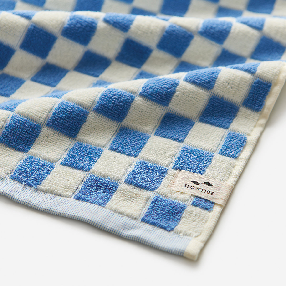 Cotton terry bath towel with blue and white checkerboard design.