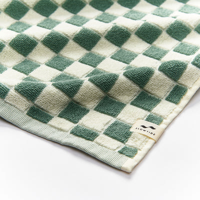 Cotton terry towel with green and cream checkerboard pattern, small label on edge.