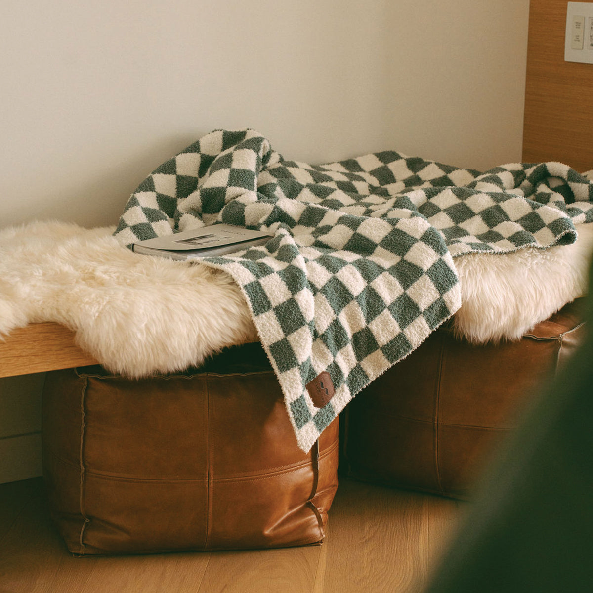 Knit throw blanket in green and white checkered pattern draped on a bench.