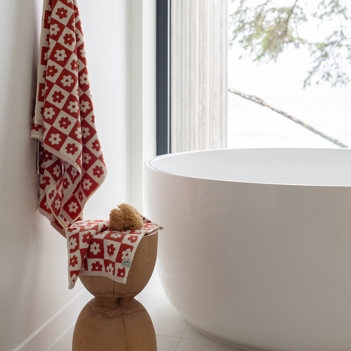 Bath towel with floral geometric pattern on display by a round tub in a modern bathroom.