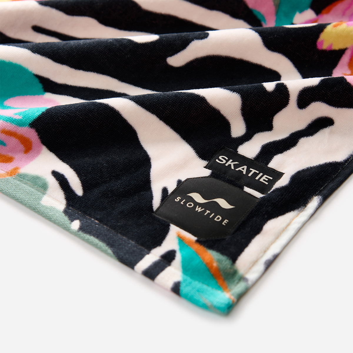 Colorful velour towel with printed pattern and small tags on the corner.