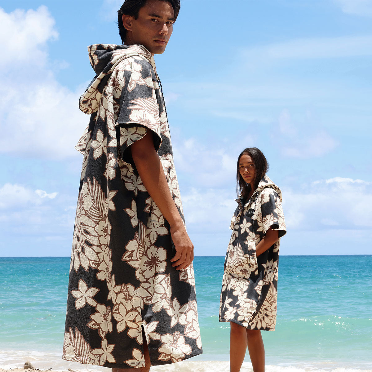 Hooded beach robes with floral print, lightweight material, shown outdoors on sand.