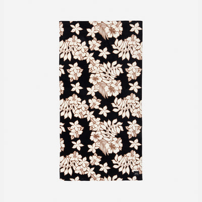 Plush velour towel with black and white floral and beige leaf print on black background.