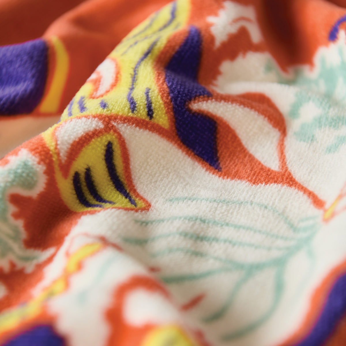 Velour towel with colorful orange, yellow, blue, and white printed pattern.