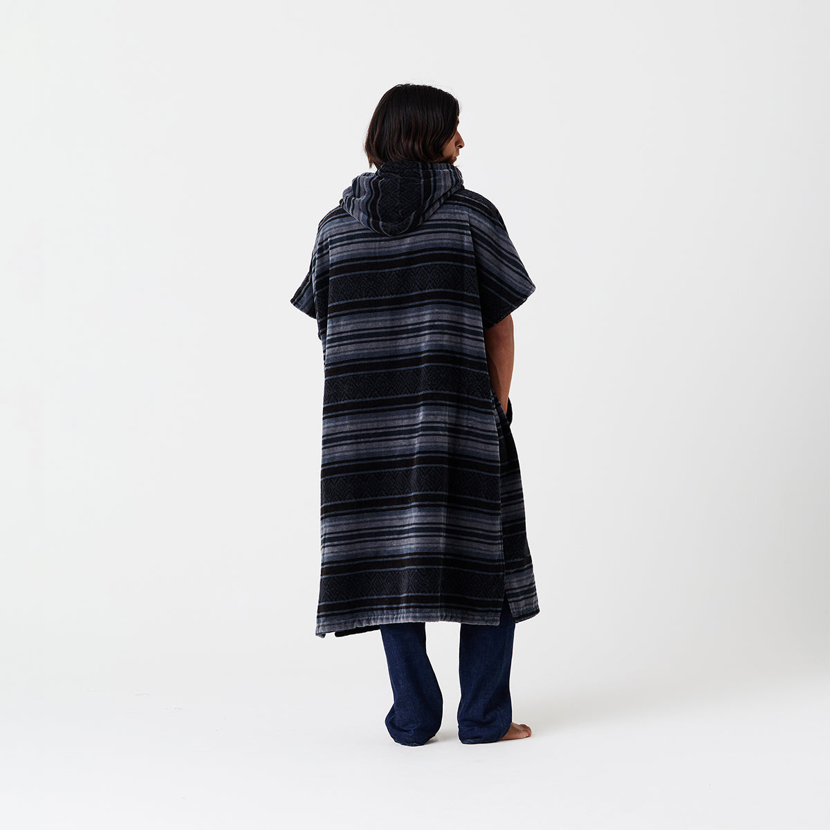 Striped hooded surf poncho with dark pants shown on barefoot model.