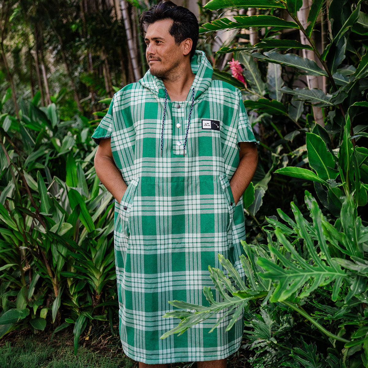 Changing poncho in green plaid, sustainable material, shown outdoors.