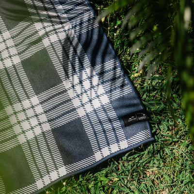 Quick-drying travel towel with partial shadow, shown outdoors on grass.