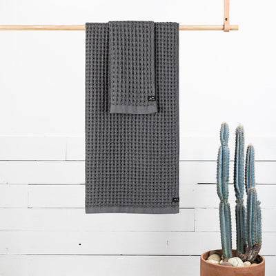 Gray waffle bath towels on wooden rod.