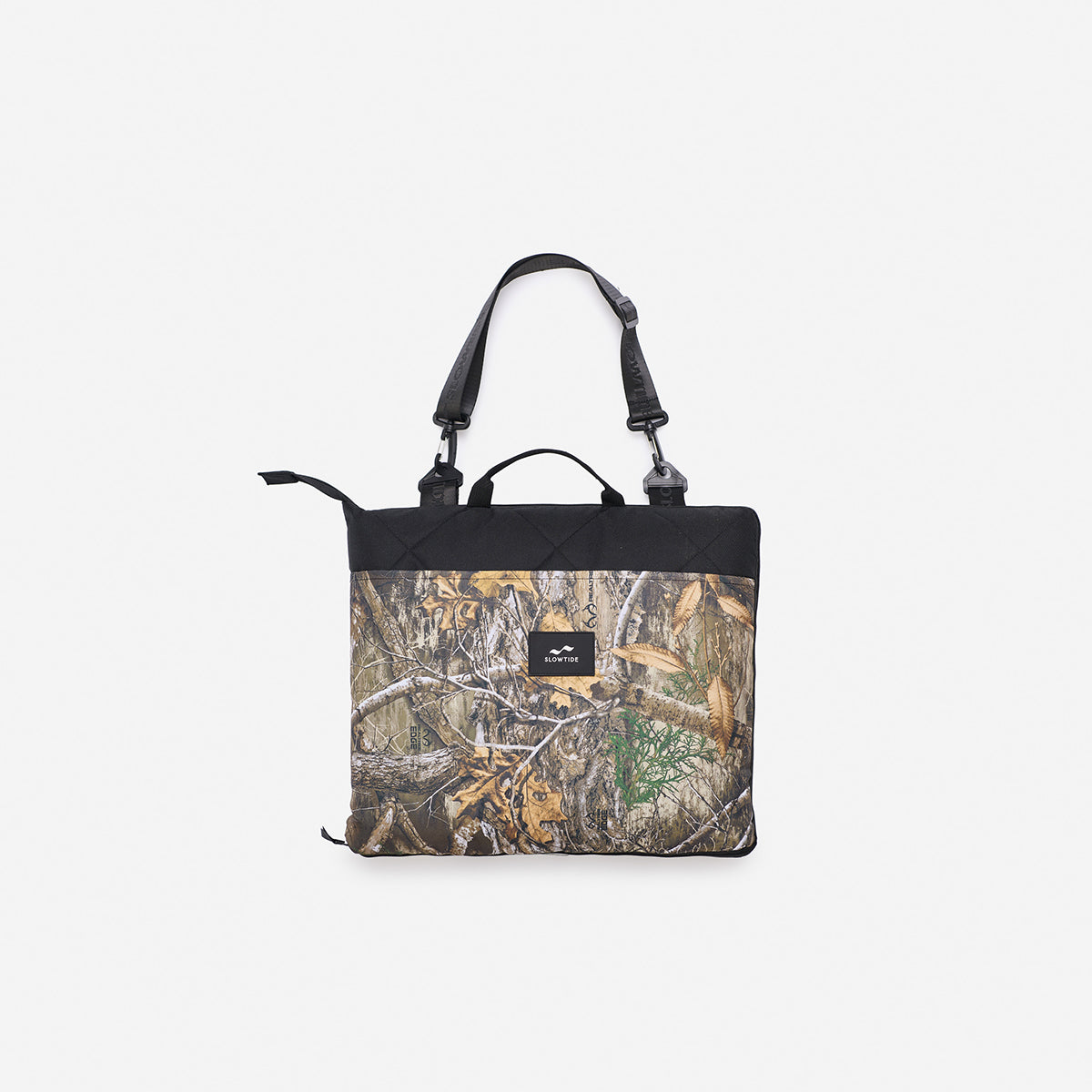 Tote bag with camo print, black handles, and small front logo patch.