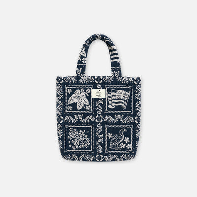 Navy tote bag with white floral, bird, and island-inspired abstract patterns.