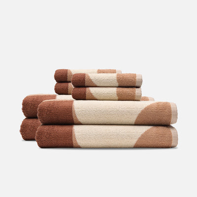 Sand-resistant bath towels stacked with a brown and beige circular pattern.