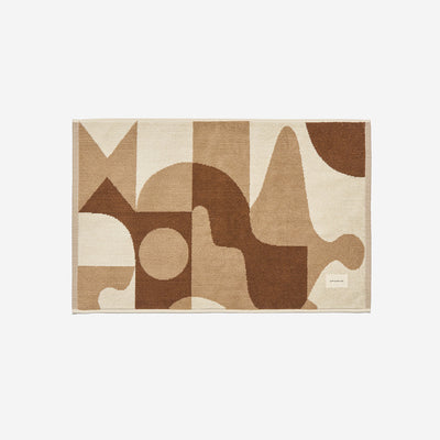 Cotton bath mat in cream and brown with an abstract geometric pattern.