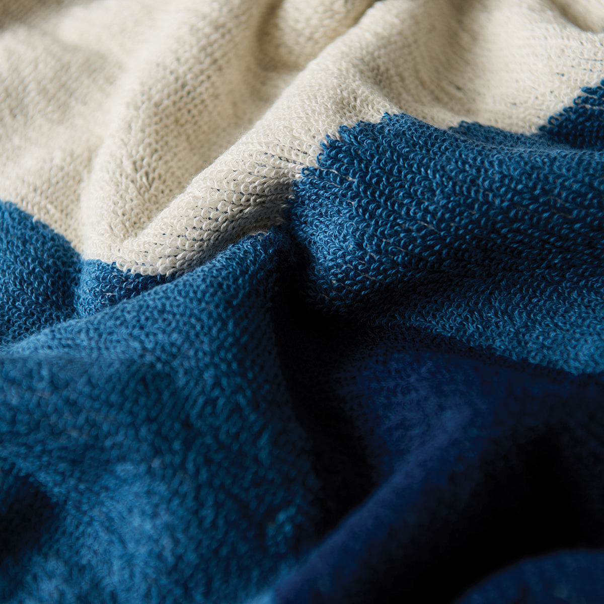 Cotton beach towel in a cream and blue color-blocked pattern for sand resistance.